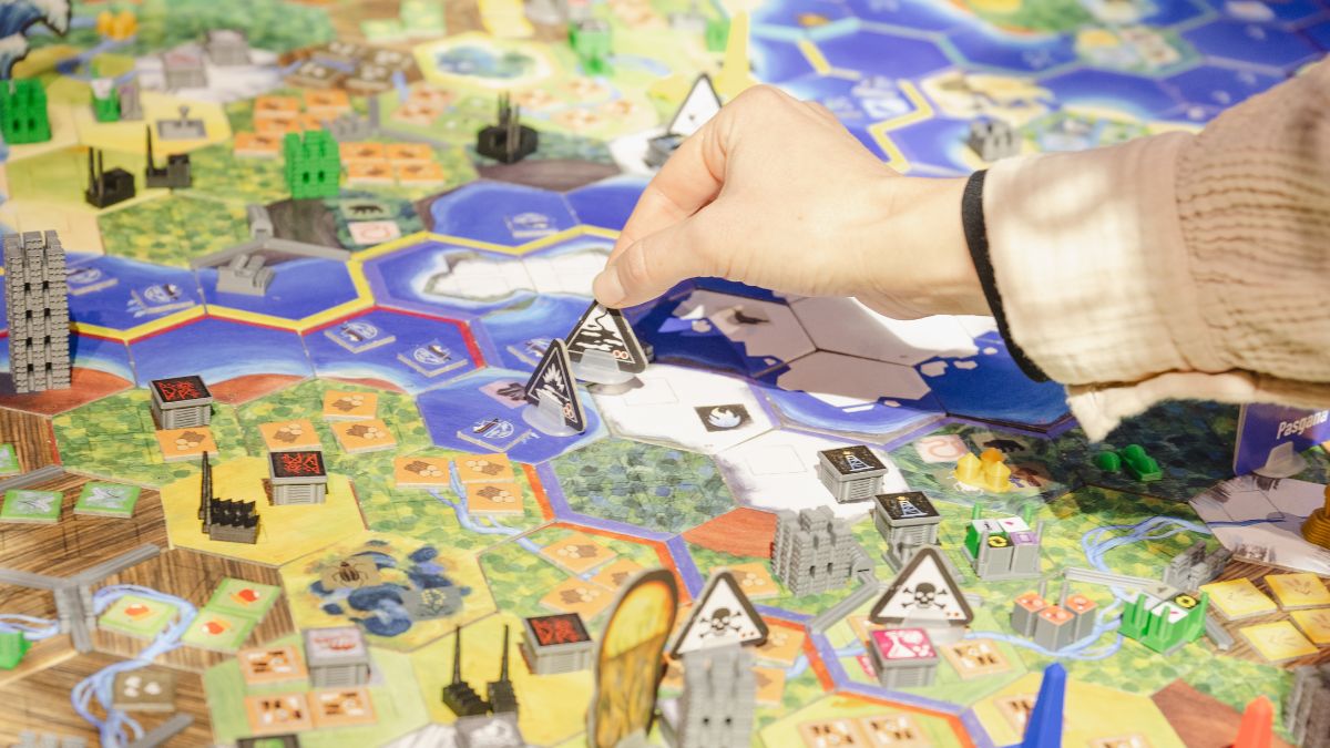 Nahaufnahme eines bunten Spielbretts mit einer Hand, die eine Spielfigur hält