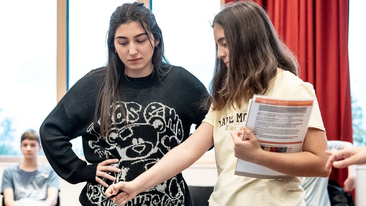Zwei junge Frauen studieren gemeinsam ein Heft