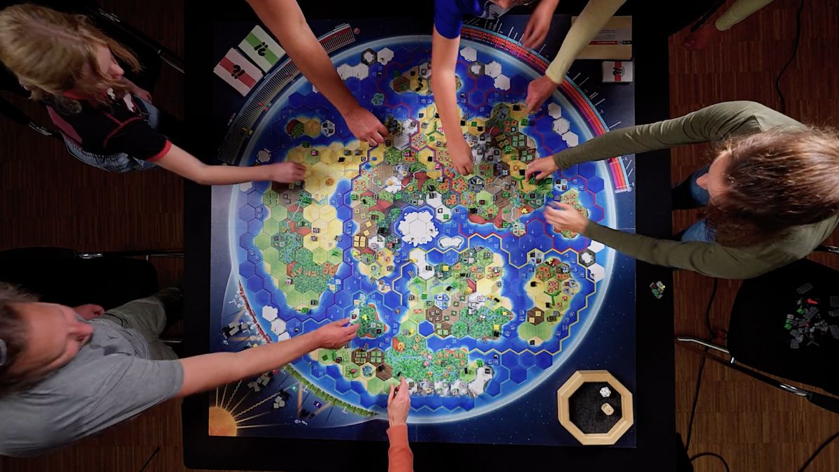 Mehrere Personen beugen sich von oben über ein großes rundes Spielbrett