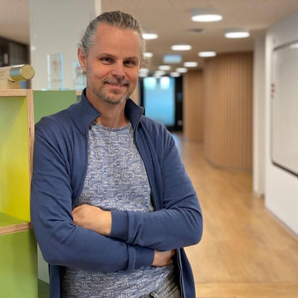 L&auml;chelnder Mann mit langen grauen Haaren vor hellem Hintergrund