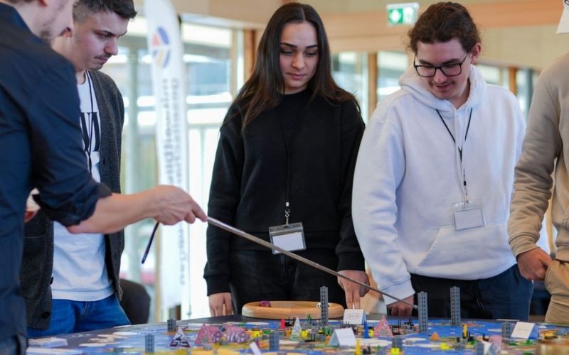 Zwei junge Menschen zeigen auf das Weltklimaspiel-Spielbrett